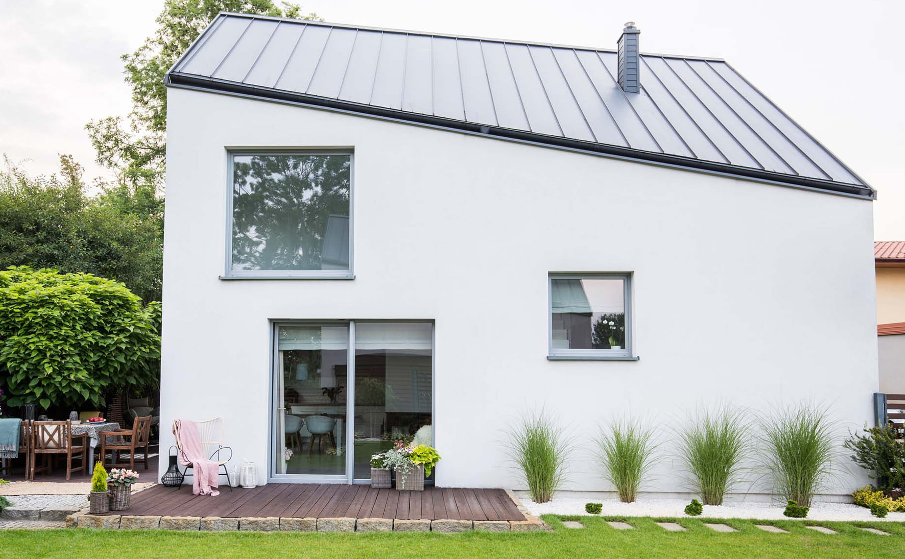Maison contemporaine avec un enduit blanc et une toiture en zinc.